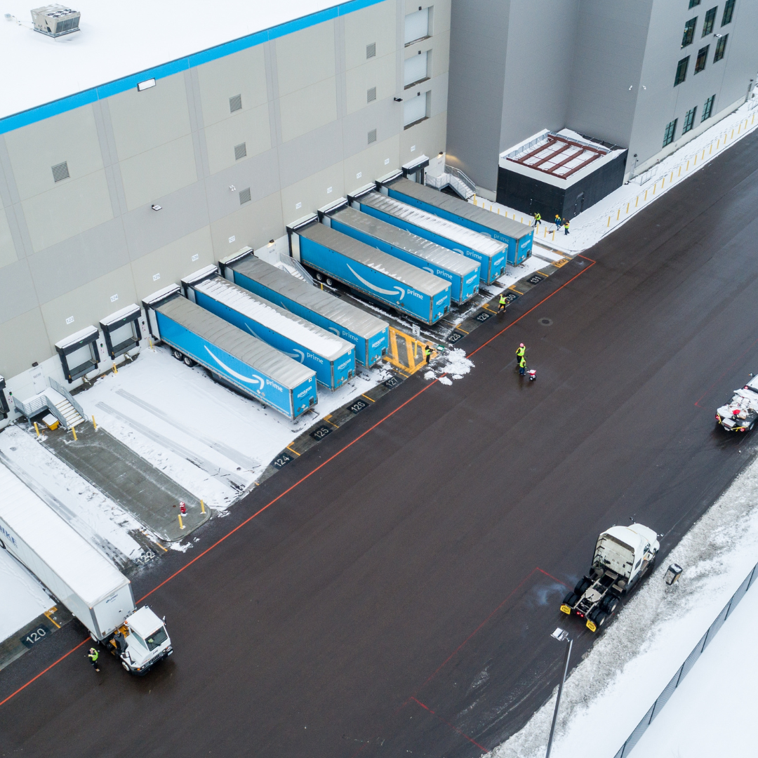Aerial view of a large warehouse with loading docks and snow-covered ground.